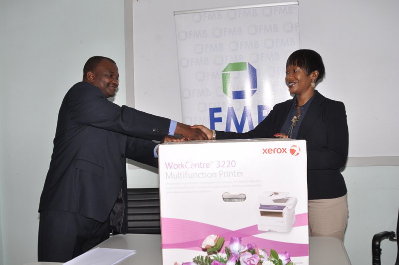 The Officer in Charge, Blantyre of the Fiscal Unit of the Malawi Police Service, receives one of the photocopier-printers from Sylvia Mataka, Head of Marketing & CSR, FMB
